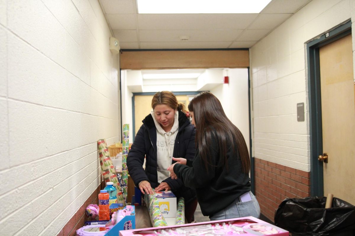 Yormari Echeverria del grado 12 de ayudar a traducir ayudó a una madre voluntaria a envolver los regalos.